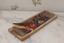 A rectangular wooden serving tray with a vintage floral print and a gold metal tongs handle, resting on a white marble countertop.